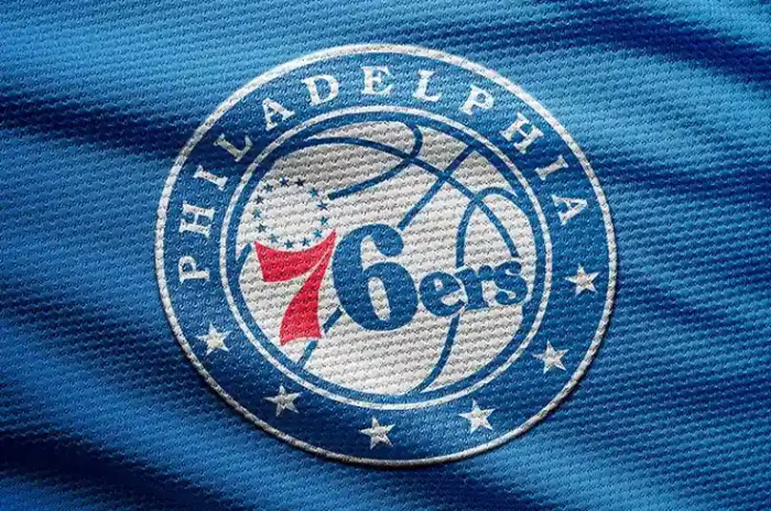 Free basketball logo mockup featuring a stitched emblem on a blue jersey fabric with high-detail texture.