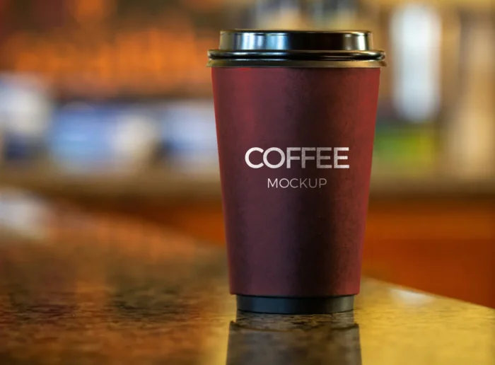 Dark-themed coffee cup mockup on a table with realistic lighting and shadows for branding design presentation.