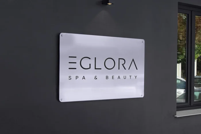 Modern spa sign mockup with sleek metallic finish, cutout text, and soft lighting on a dark wall backdrop.